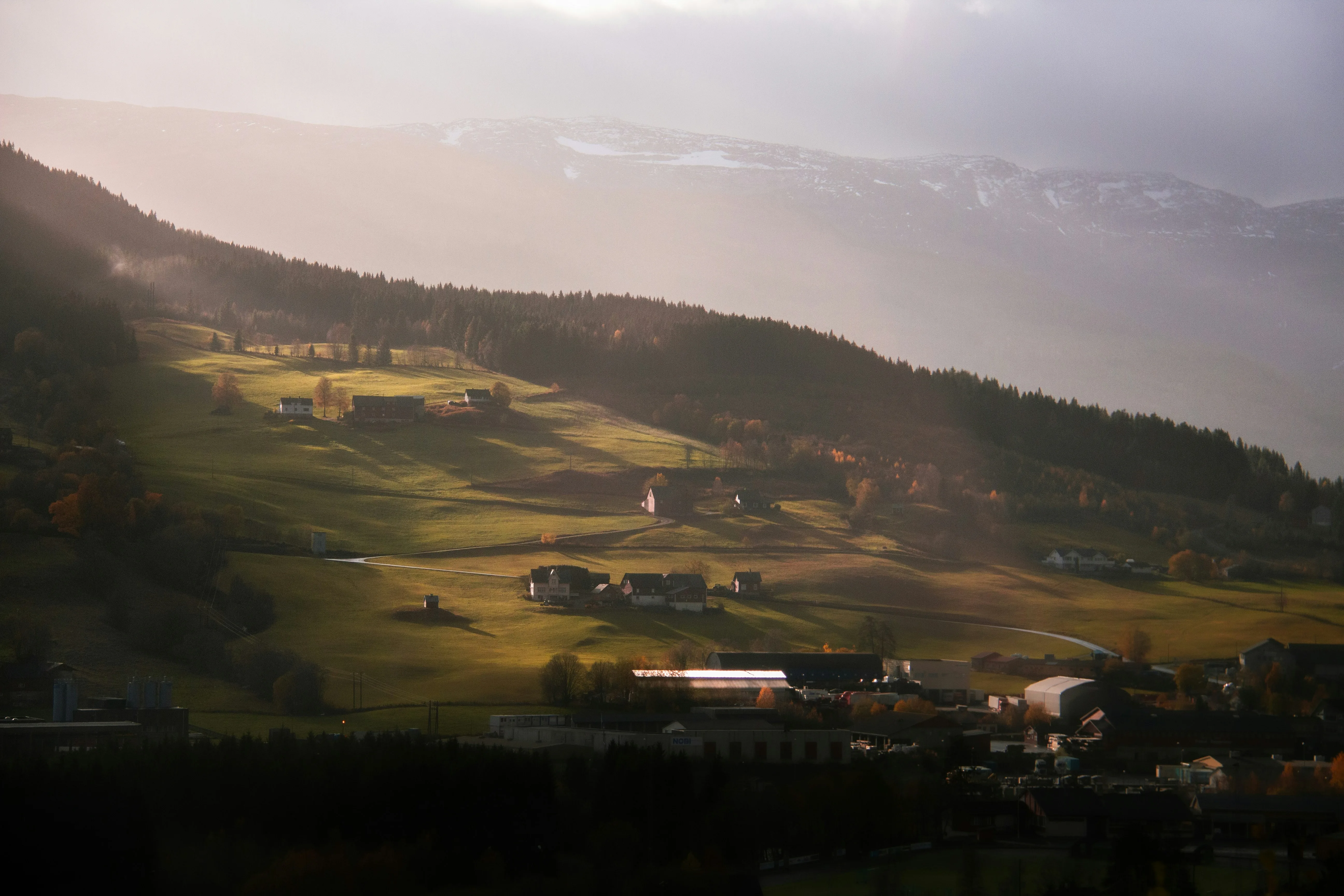 Norsk bygd i åsside med gyllent kveldslys