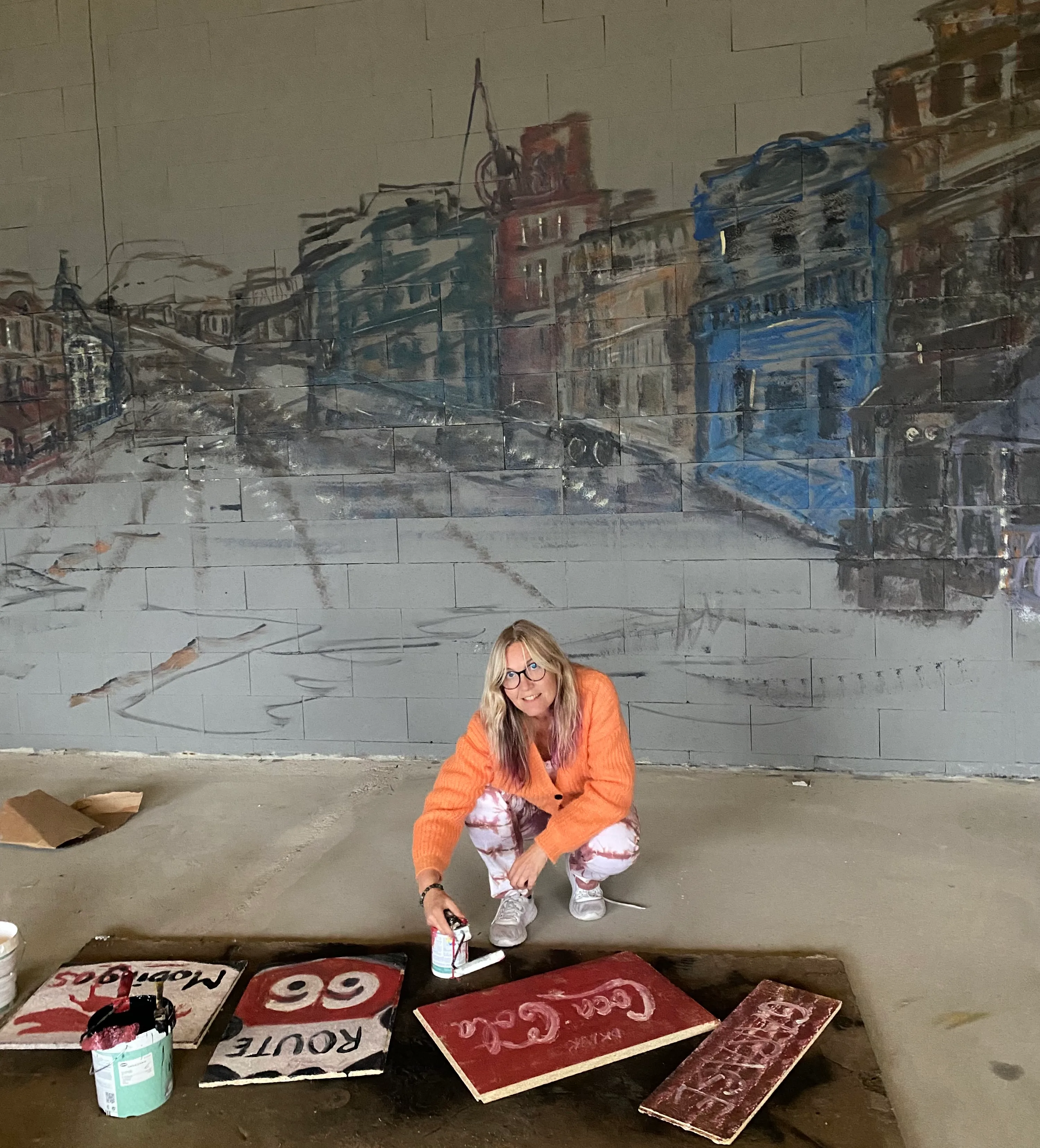 Linda Nogva Vedeld painting a large colorful mural outdoors