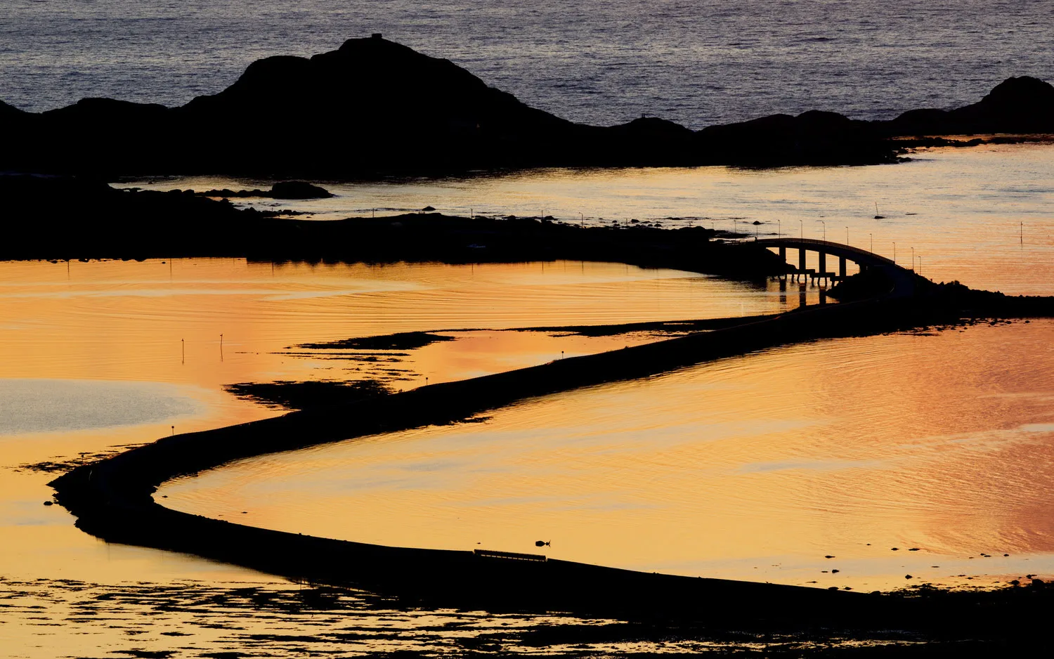 Coastal road winding along Nordøyane’s shoreline at sunset