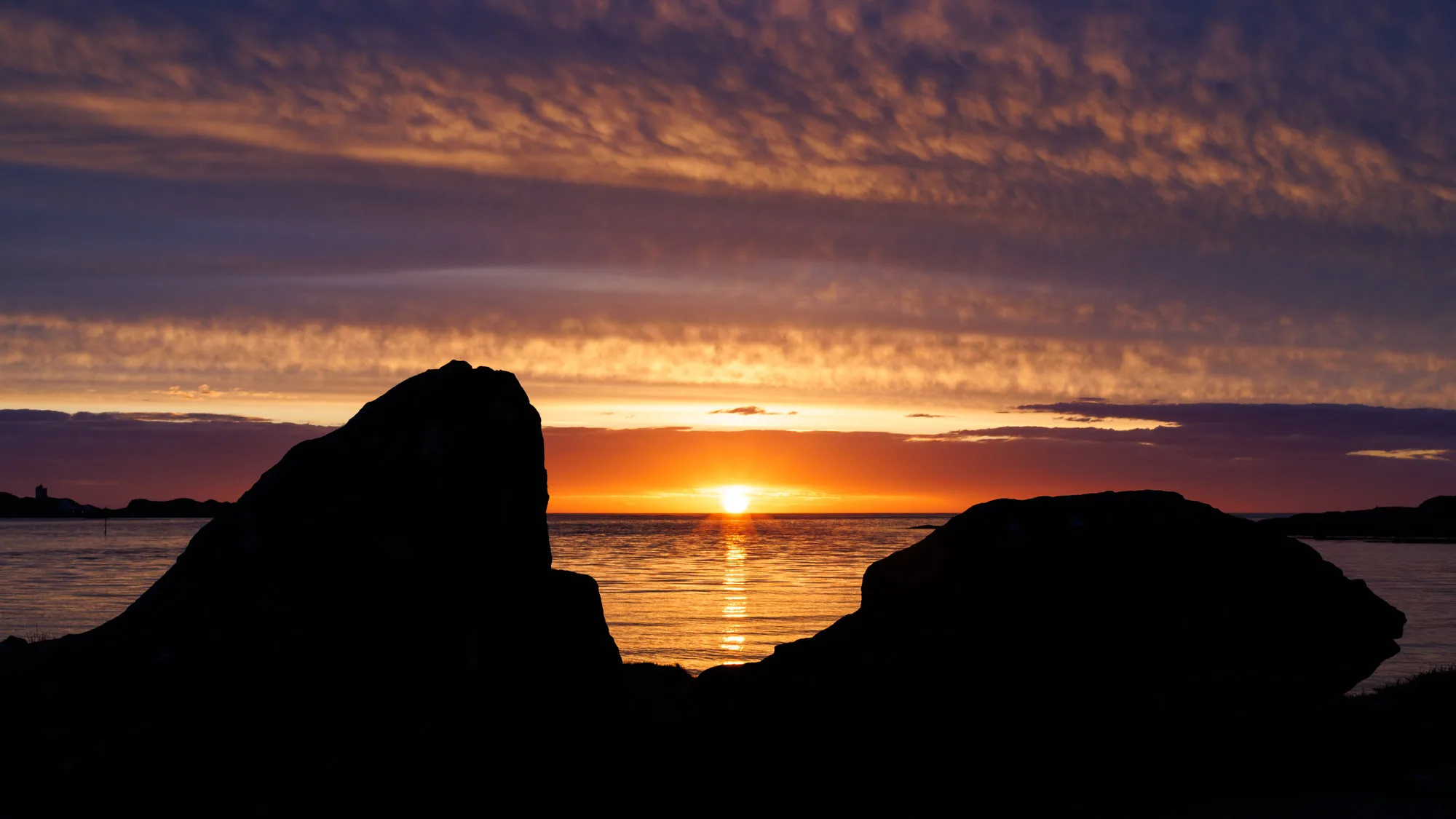 Dramatic sunset silhouetting sea stacks along Nordøyane’s coast