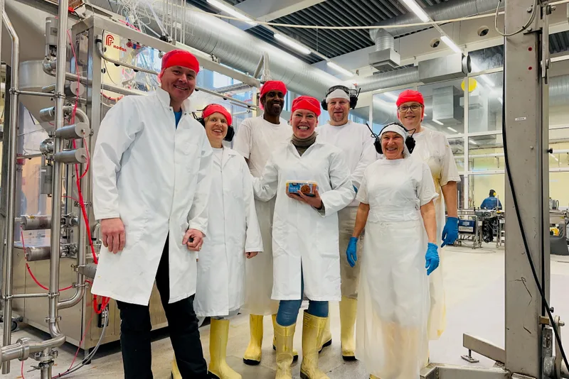 The Primar bacalao factory crew posing together in white coats and red caps in the production facility