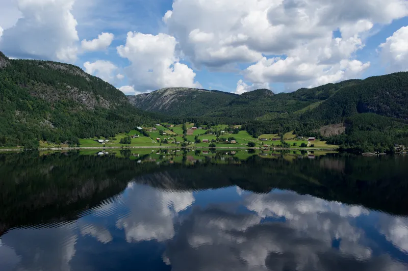 Byglandsfjorden lake surrounded by green mountains with mirror-still reflections on the water