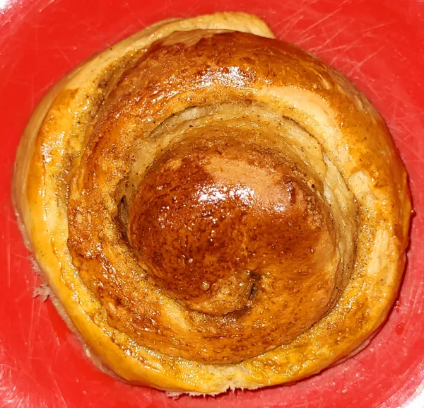 Freshly baked cinnamon bun close-up showing golden-brown cinnamon swirl