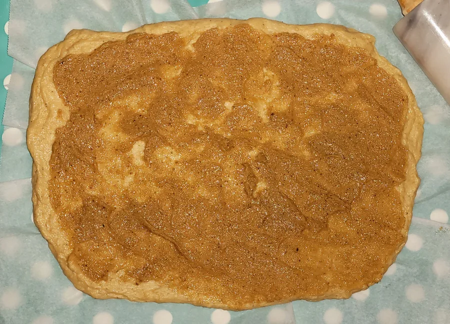 Rolled-out dough covered with cinnamon-butter filling on a polka-dot tablecloth