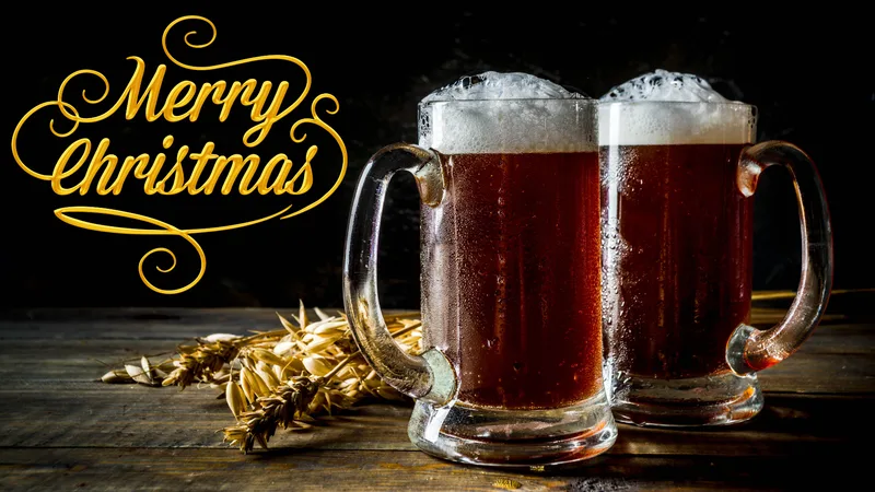 Two mugs of foaming dark Christmas beer on a wooden table with Merry Christmas in gold lettering