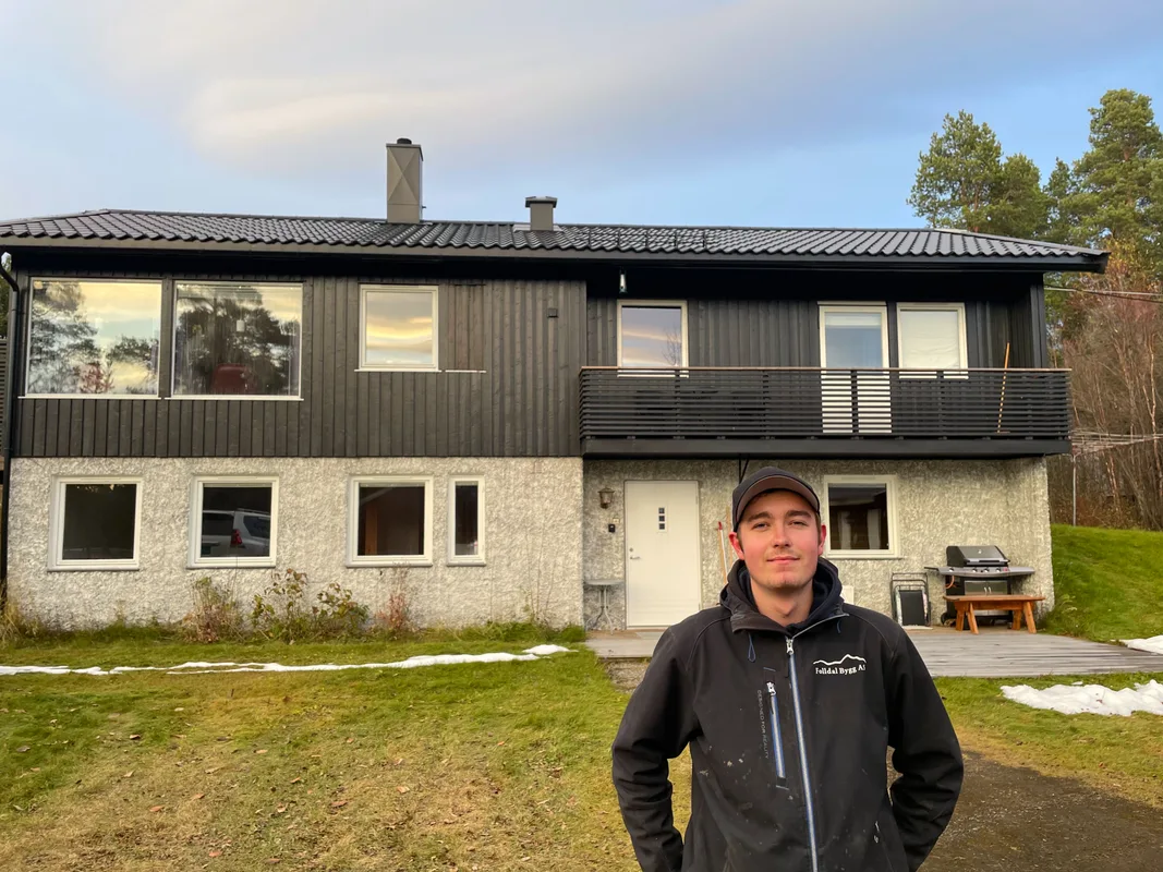 Adrian Solly standing in front of his brown two-story house with a spacious garden in Folldal