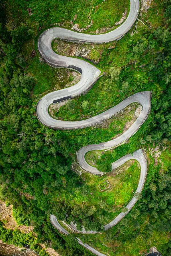 Aerial view of a winding road through lush green Norwegian forest