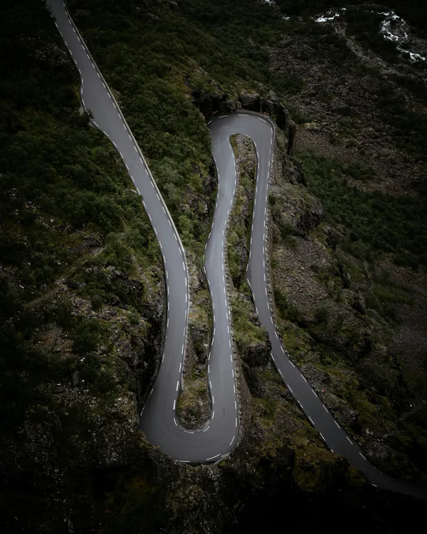 Aerial view of a dramatic hairpin turn on a mountain road at dusk
