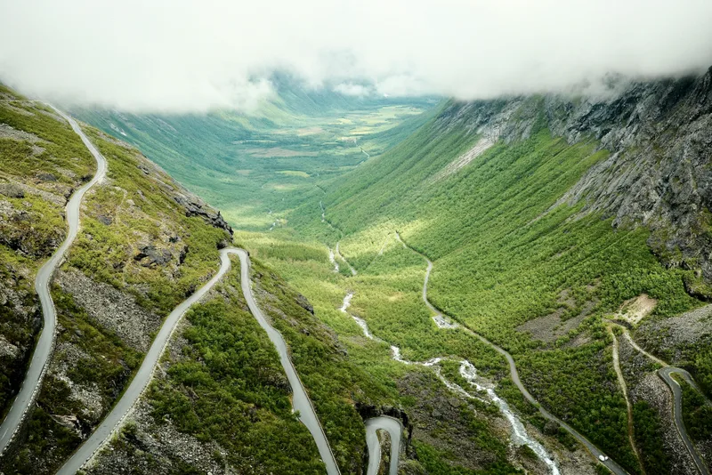 Aerial view of Trollstigen switchback road winding up a steep green mountainside in Norway