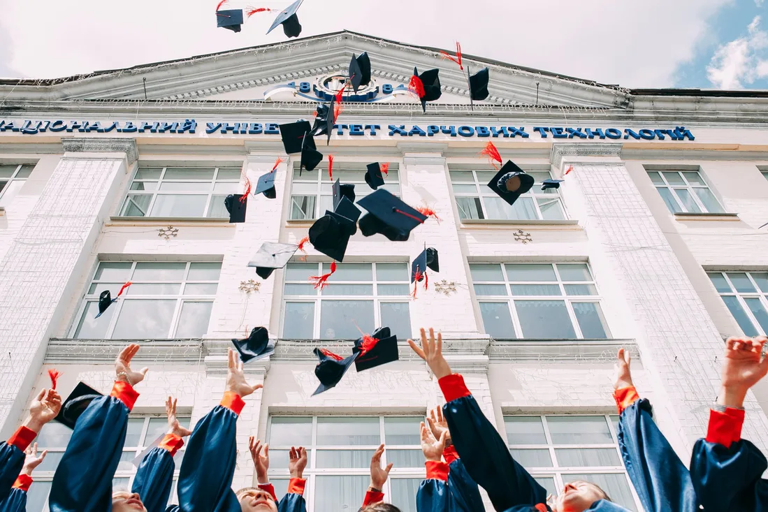 Happy graduates celebrating in caps and gowns throwing their mortarboards in the air