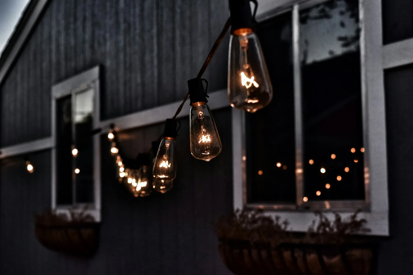 Warm hanging garden lights glowing beside a house at dusk