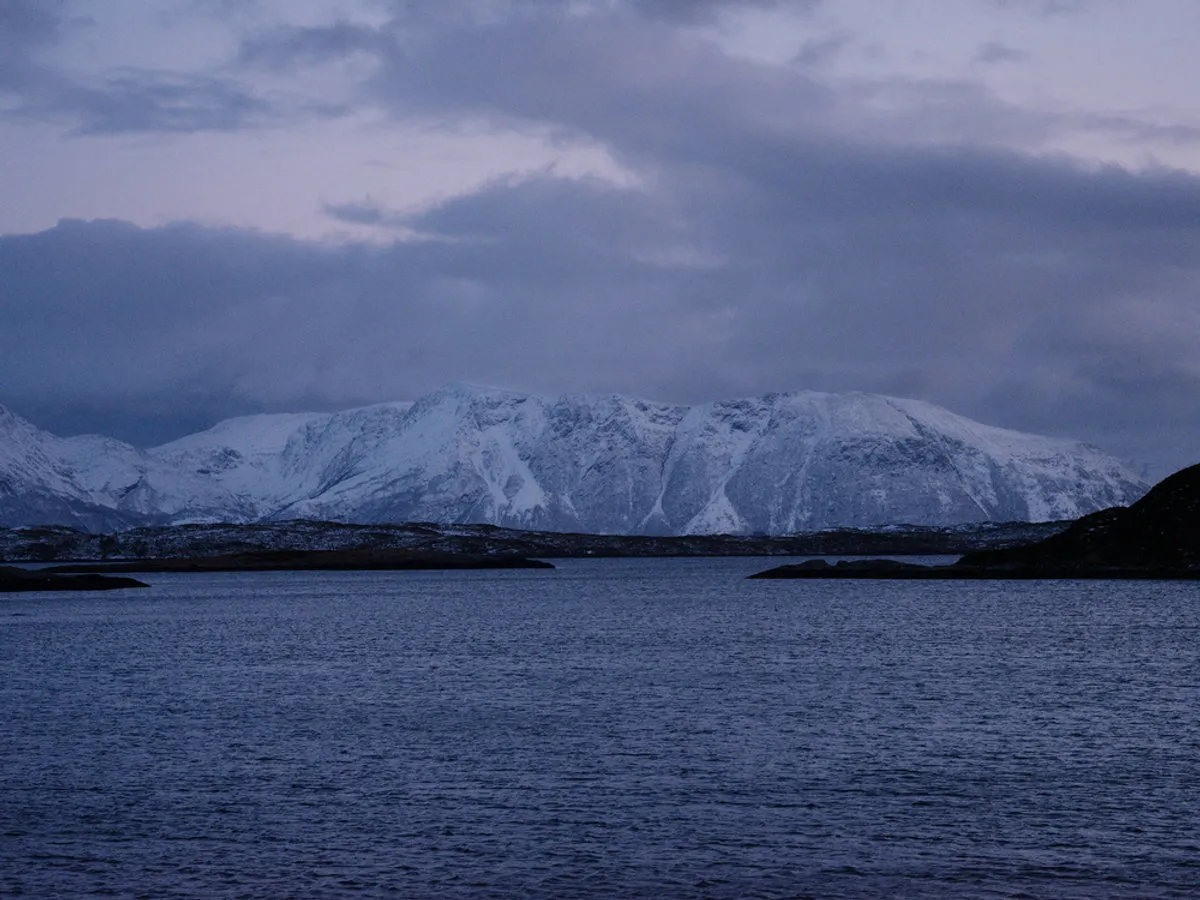 Snow-covered mountains rising behind the coastal village of Aukra