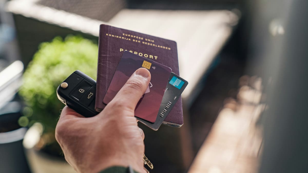 A hand holding a passport, bank card, and car keys — the kind of documents you need when opening a Norwegian bank account