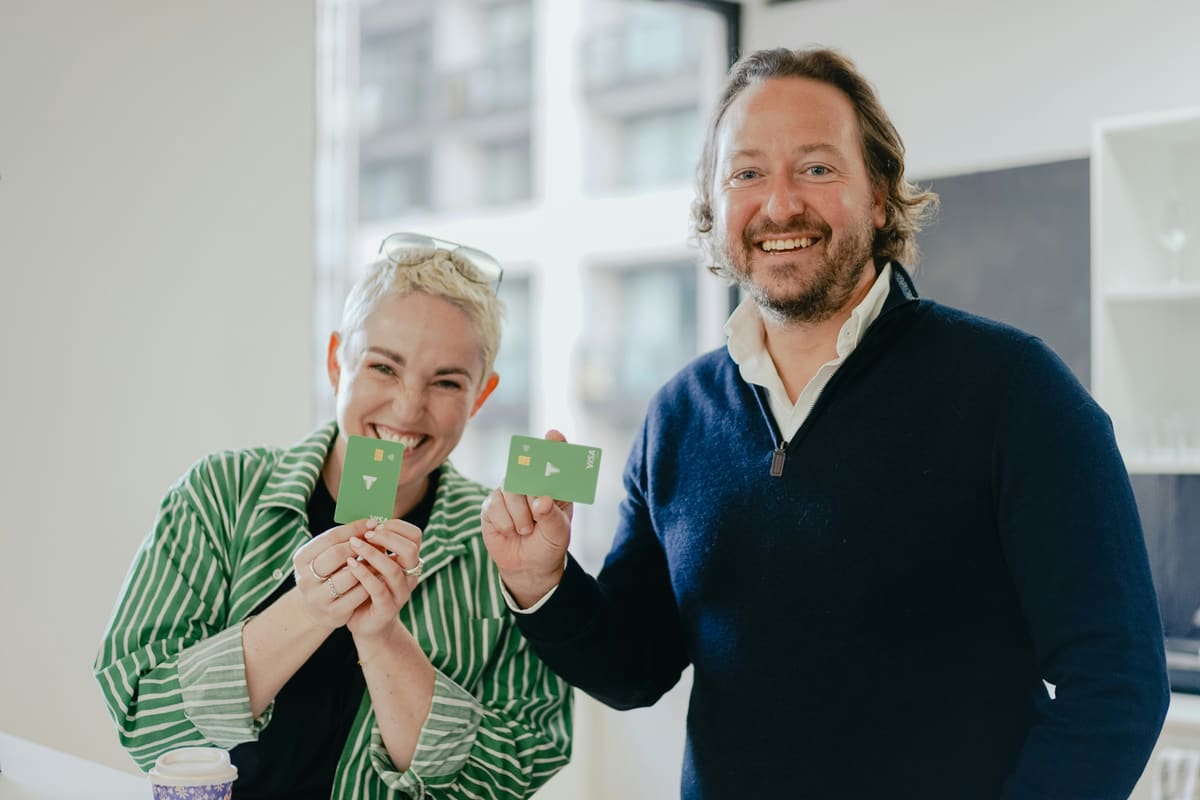 Two smiling people proudly holding up their new bank cards