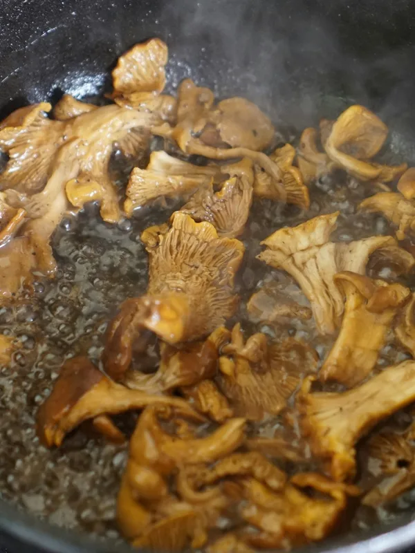 Sautéed chanterelles sizzling in a cast-iron pan on a stovetop