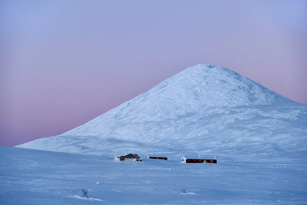 The mountain Muen bathed in the famous blue-purple Rondane light at dusk, with layered mountain ridges fading into the distance