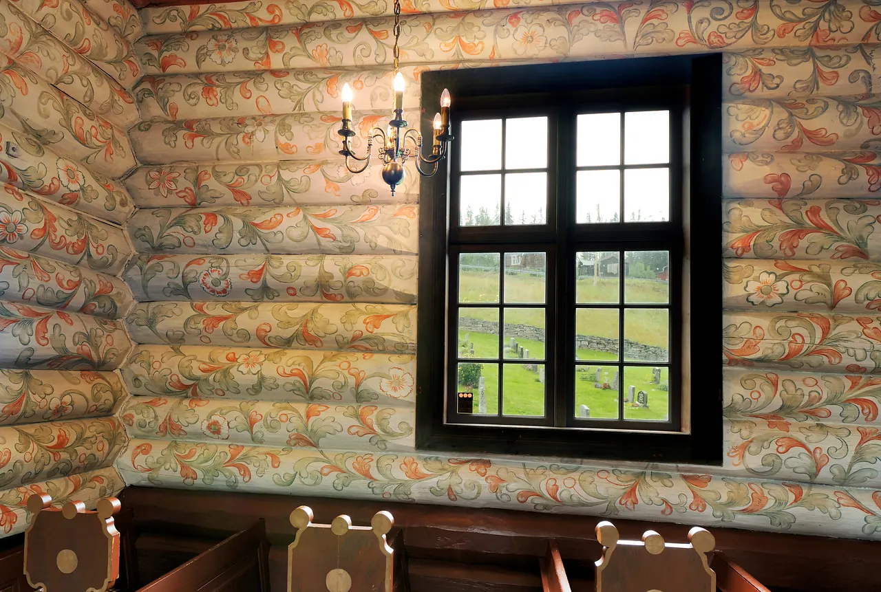 Painted wooden walls inside Sollia Church from 1737, with folk art decorations in warm colors covering the walls and ceiling