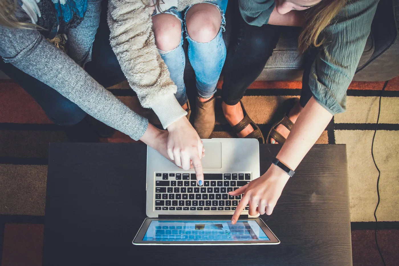 Three young people pointing at a laptop screen while studying together