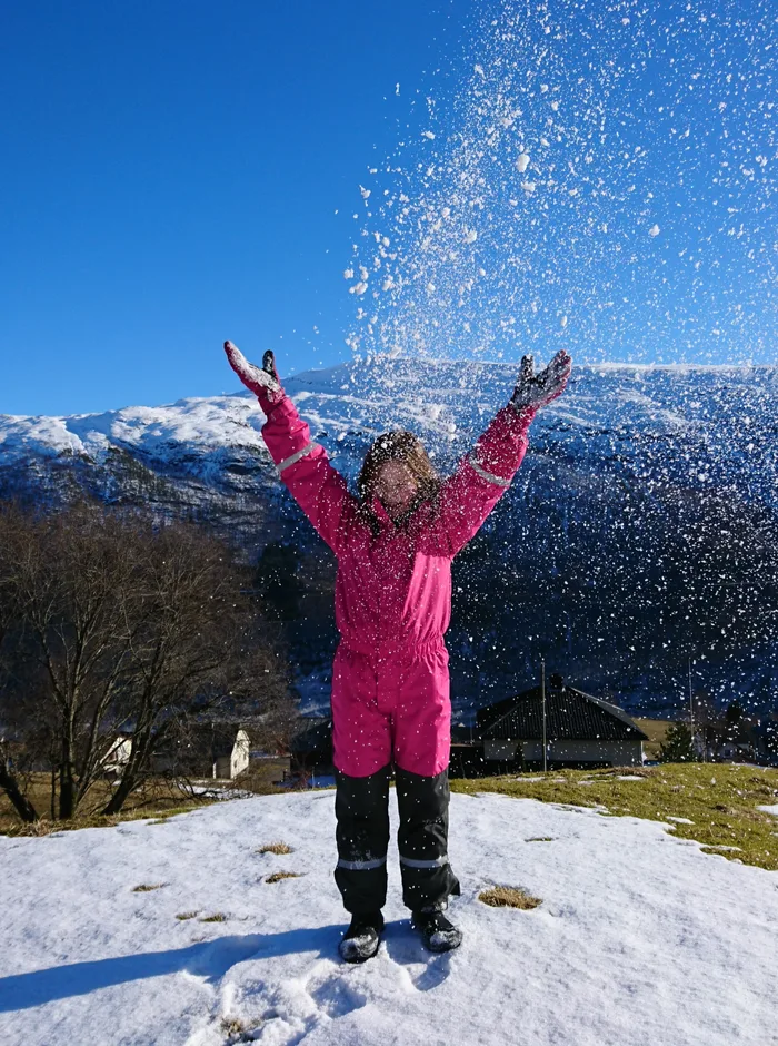 A girl throwing snow into the air during winter break