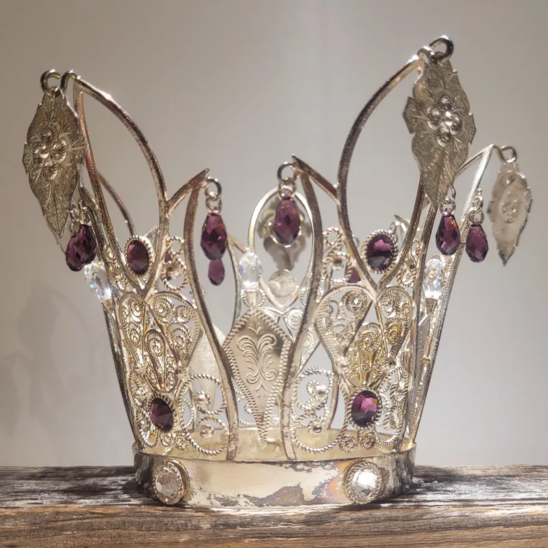 An ornate silver bridal crown with filigree work and purple gemstone droplets, crafted in the Setesdal tradition