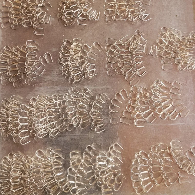 Rows of tiny silver wire loops and clusters arranged on a workbench, ready to be assembled into a brooch