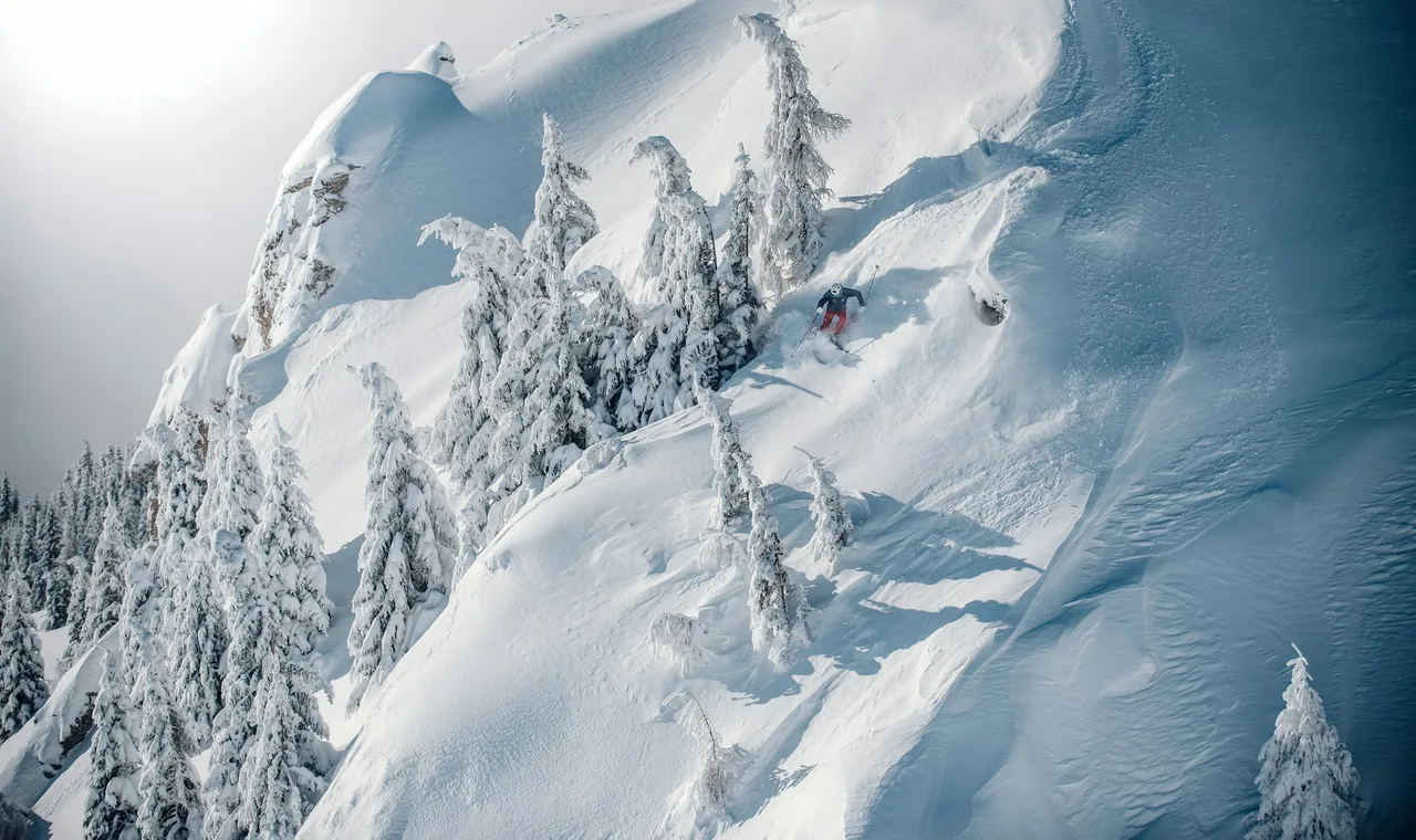 A skier carving through deep powder snow on a mountain slope