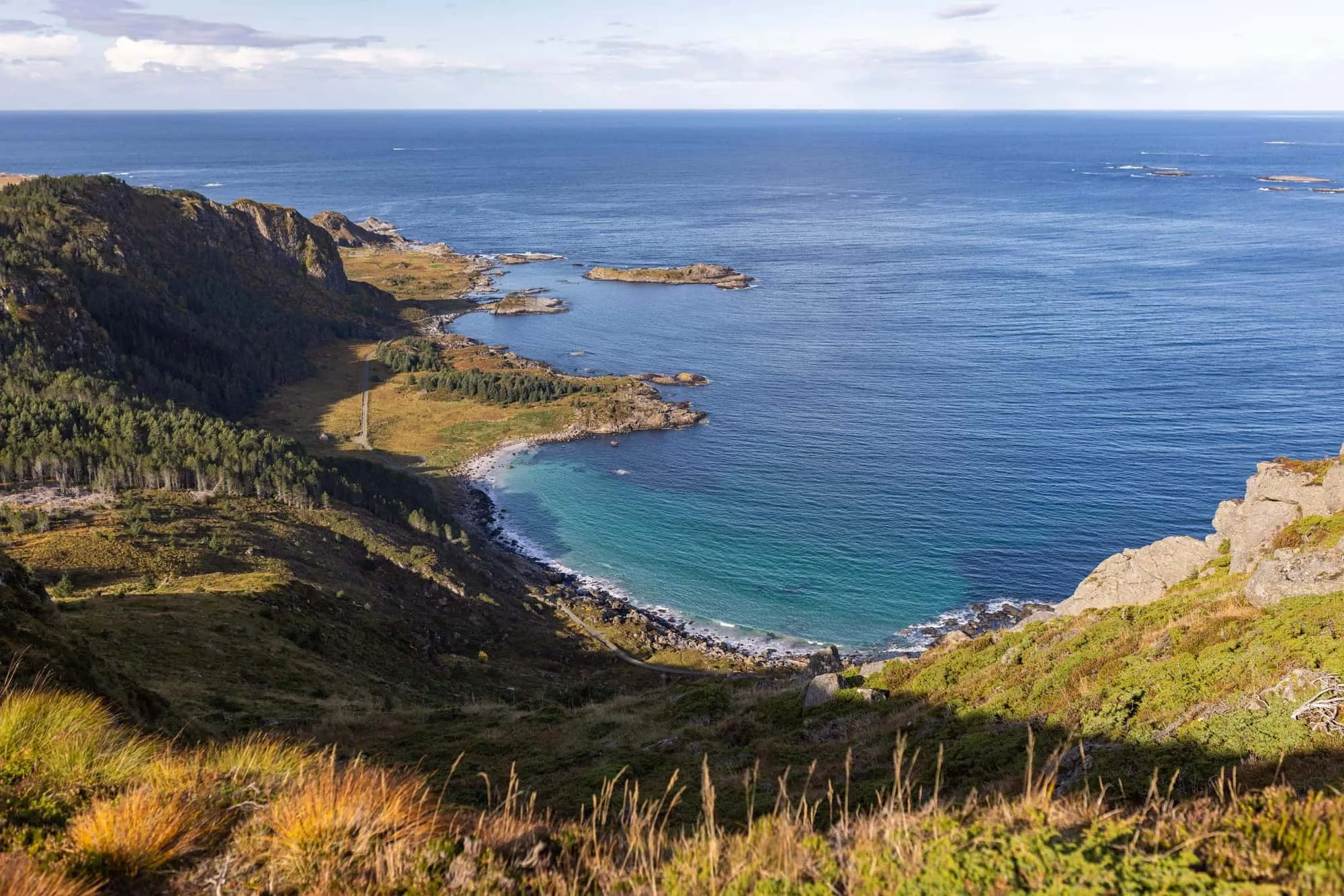 The coast of Nordøyane with sandy beaches, green mountains and forests meeting the sea