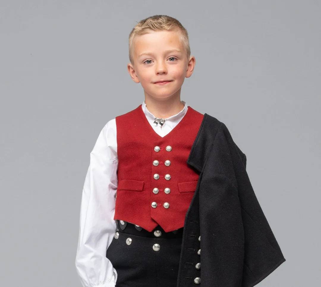 A boy wearing the traditional Sunnmøre children’s bunad with red vest and white stockings