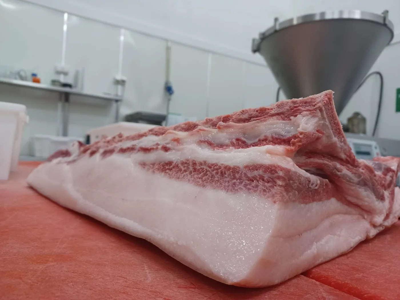 A large cut of marbled Mangalitsa pork belly on a butcher block, showing the distinctive layers of fat and meat