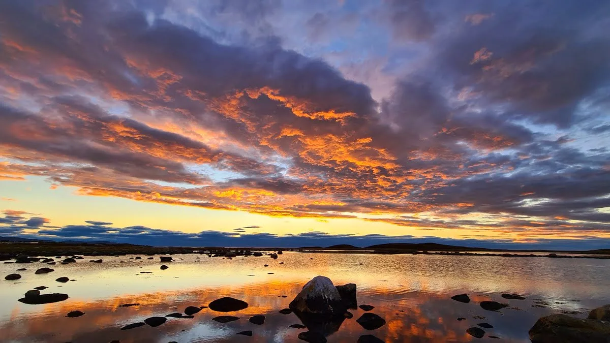 Dramatic sunset sky reflected in the calm waters of Harøya