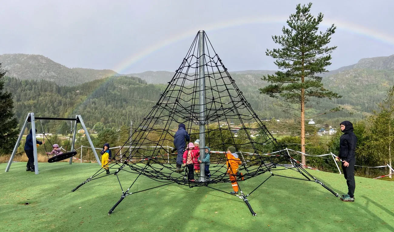 Children on a modern playground with the rainbow in the background
