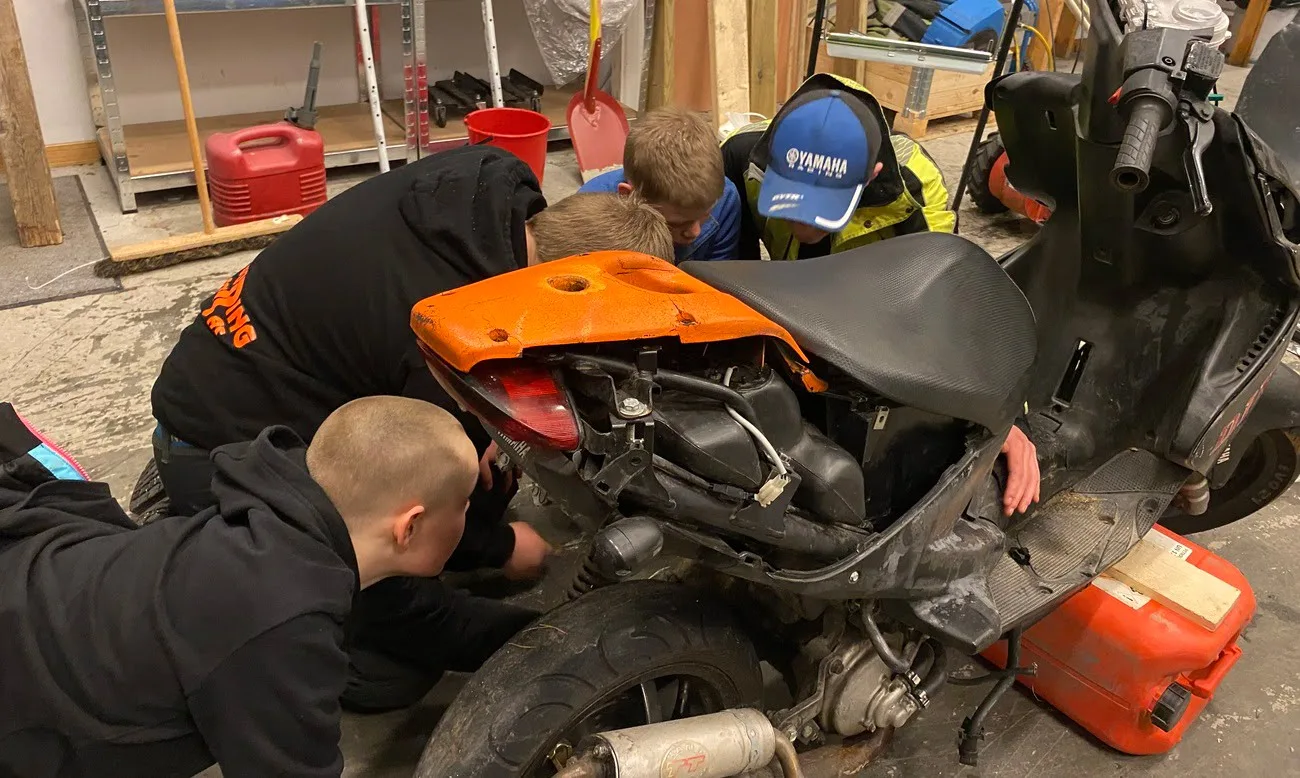 Young boys working on repairs on a moped