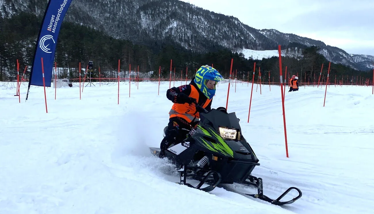 A boy rides a snowmobile on a track