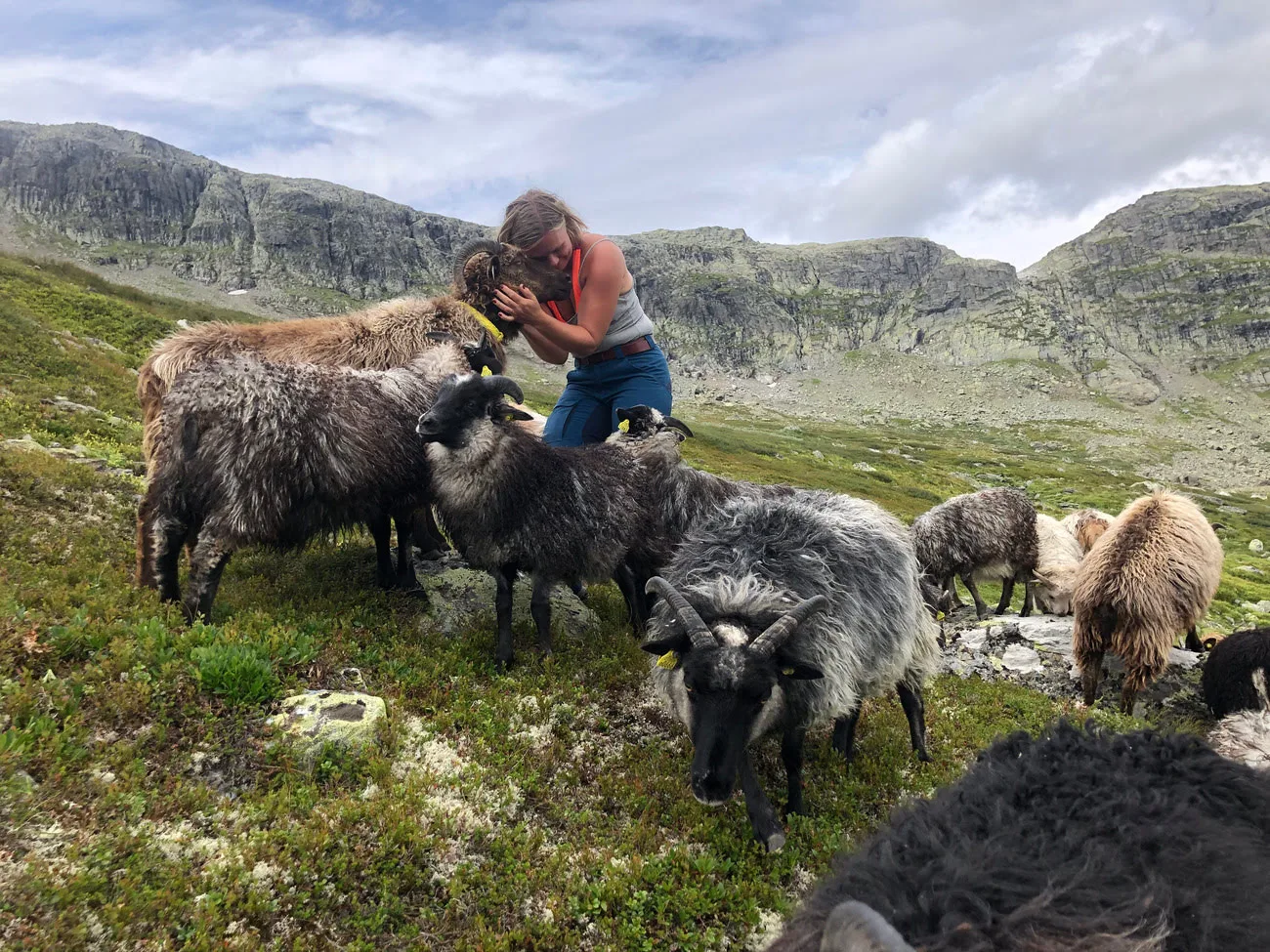 Ingunn Stræte in nature giving a hug to a sheep
