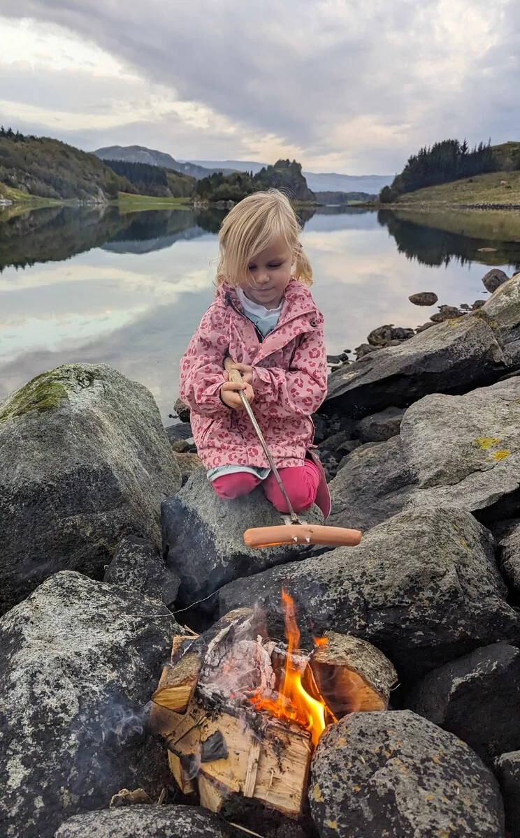 Girl grilling a sausage on a fire