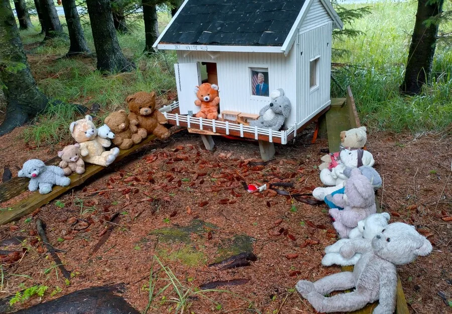Teddy bears outside a small wooden house