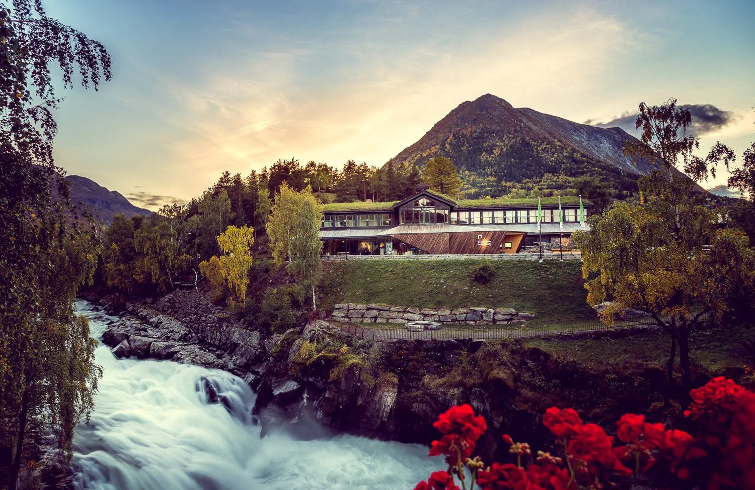 A public building located along the river. The building is made of wood with a grass roof