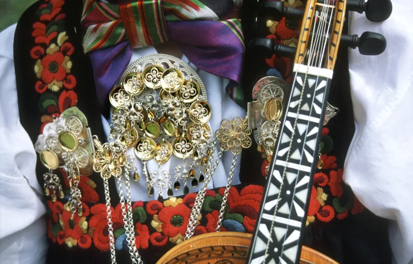 A lady in a traditional costume and a Hardanger fiddle