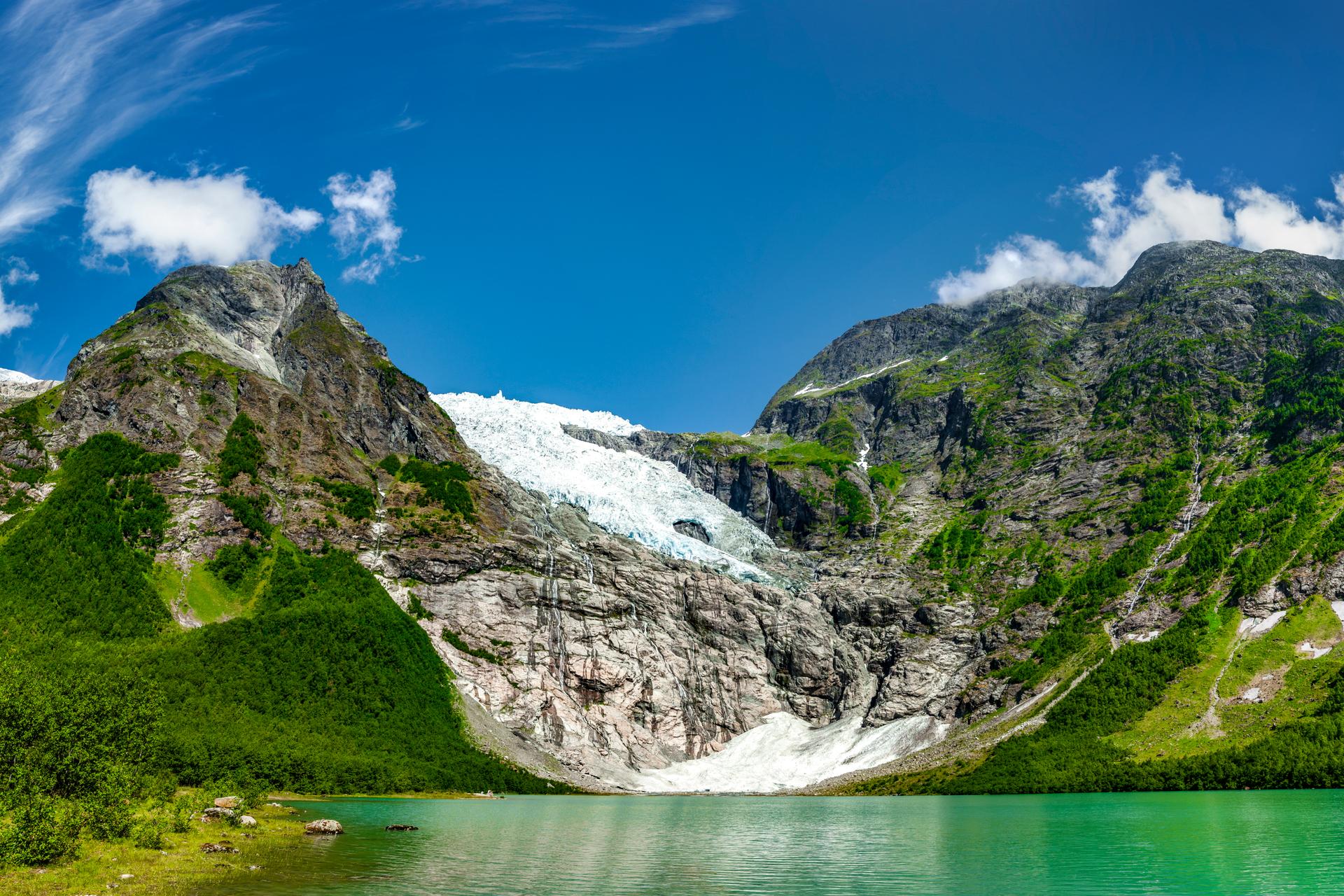 Bøyabreen glacier descending between green mountainsides into a turquoise glacial lake in Fjærland